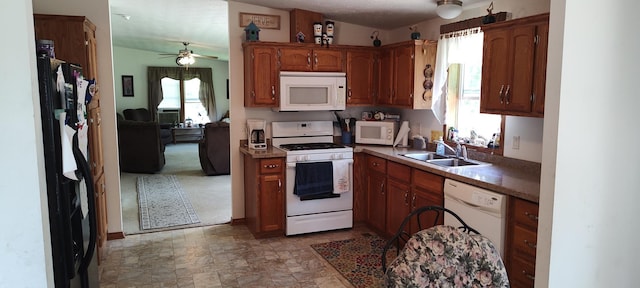 kitchen with a ceiling fan, a sink, white appliances, stone finish flooring, and brown cabinetry