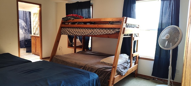 bedroom featuring light colored carpet, baseboards, and connected bathroom