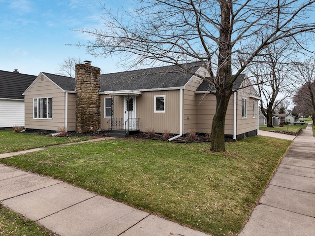 view of front of home featuring a chimney, a shingled roof, and a front yard