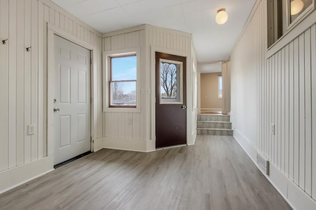 foyer entrance featuring baseboards, wood finished floors, visible vents, and plenty of natural light