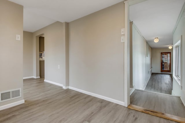 spare room with baseboards, light wood-style floors, and visible vents