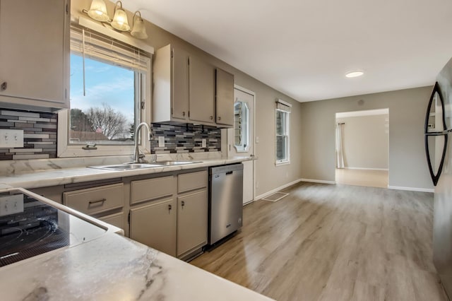 kitchen with black appliances, a wealth of natural light, a sink, and light countertops