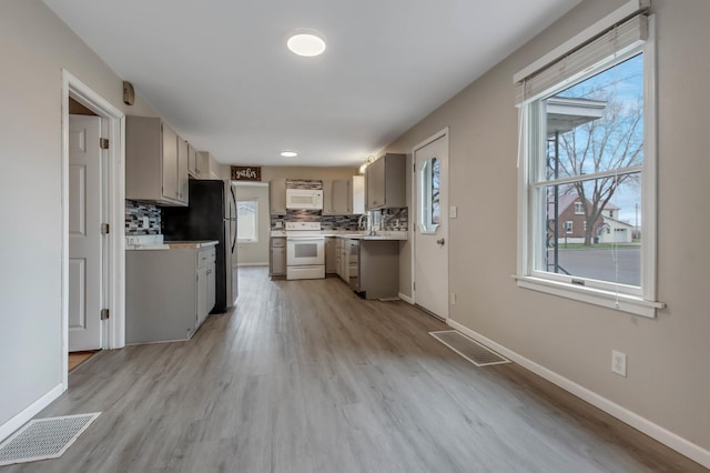 kitchen with light countertops, visible vents, backsplash, and white appliances