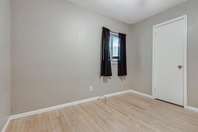 spare room with baseboards and wood finished floors
