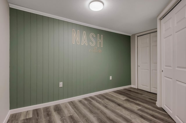 unfurnished bedroom with crown molding, baseboards, a closet, and dark wood-style flooring