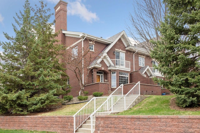 view of front facade with a chimney, a front yard, and brick siding