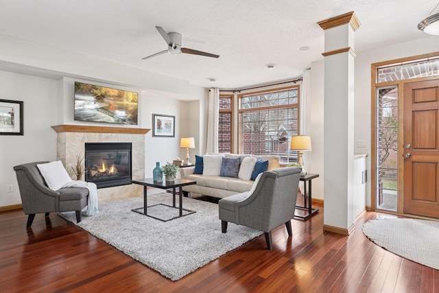 living room featuring baseboards, a ceiling fan, wood finished floors, and a tiled fireplace