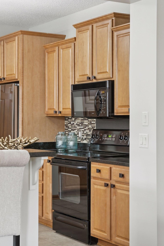 kitchen with light brown cabinetry, dark countertops, backsplash, and black appliances