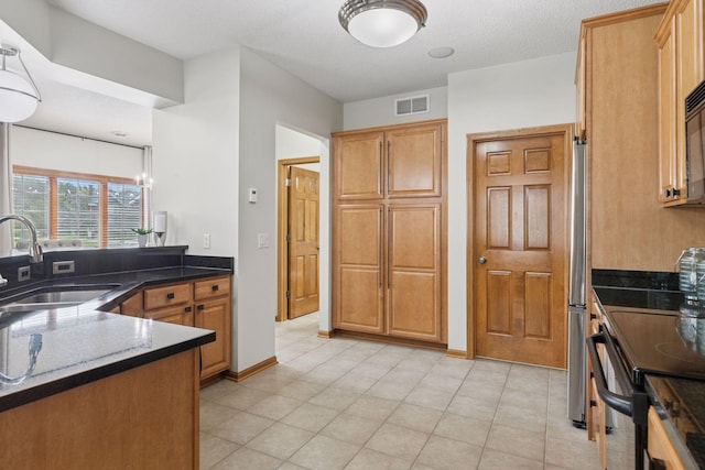 kitchen with dark stone counters, range with electric cooktop, visible vents, and a sink