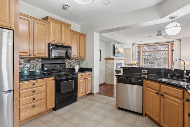 kitchen with a ceiling fan, a fireplace, tasteful backsplash, a sink, and black appliances