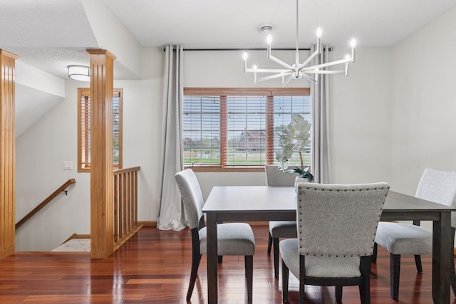 dining space with baseboards, decorative columns, wood finished floors, and a chandelier