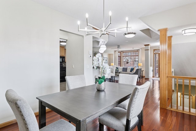 dining space featuring a notable chandelier, decorative columns, and wood finished floors