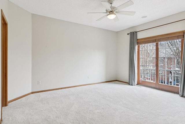 carpeted spare room featuring a ceiling fan and baseboards