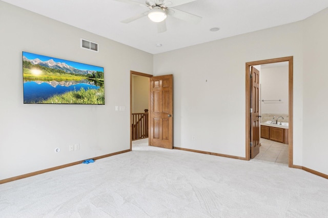 unfurnished bedroom featuring a ceiling fan, visible vents, baseboards, connected bathroom, and light carpet