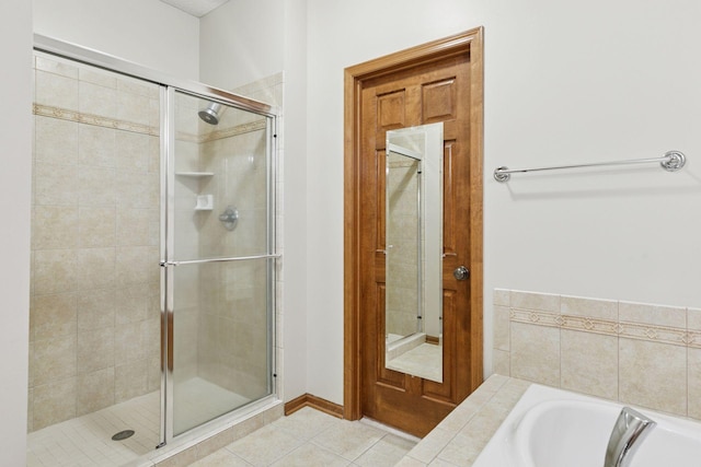 bathroom featuring tile patterned flooring, a stall shower, and a bath