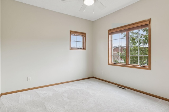 spare room with visible vents, a ceiling fan, baseboards, and light colored carpet