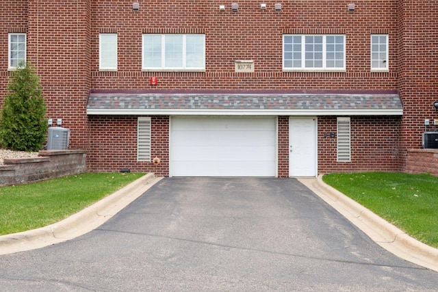 view of front of property with central air condition unit, brick siding, an attached garage, and aphalt driveway