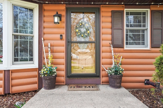 view of exterior entry with a porch and log veneer siding
