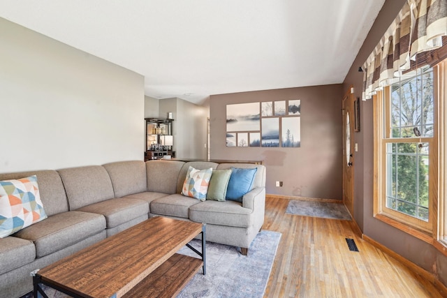 living room with baseboards, light wood finished floors, and visible vents