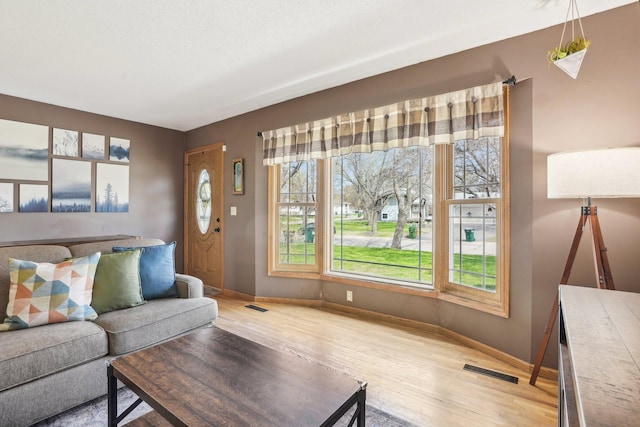 living area featuring baseboards, visible vents, and light wood-style floors