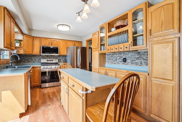 kitchen featuring appliances with stainless steel finishes, tasteful backsplash, open shelves, a sink, and light wood finished floors