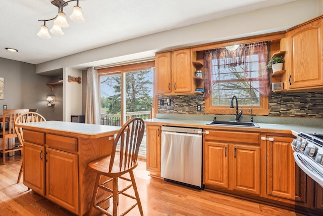 kitchen with light countertops, appliances with stainless steel finishes, a sink, and light wood-style floors
