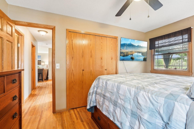 bedroom with light wood-type flooring, baseboards, ceiling fan, and a closet