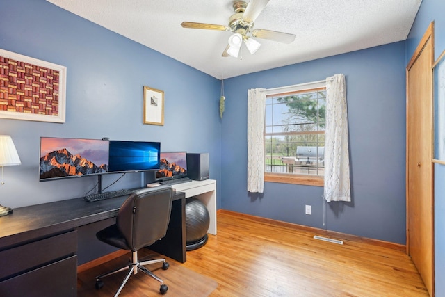 home office featuring baseboards, ceiling fan, wood finished floors, and visible vents