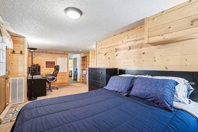 bedroom with carpet, wood walls, a textured ceiling, and visible vents