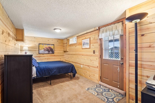 bedroom featuring wooden walls, carpet flooring, and a textured ceiling