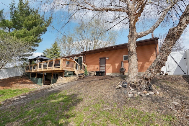 rear view of house featuring fence and a wooden deck