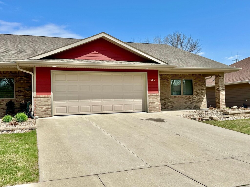 505 Barck Ave, Luverne, MN 56156 - view of front of house with a garage, brick siding, a shingled roof, and concrete driveway
