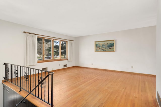 unfurnished room featuring baseboards, light wood-style flooring, and visible vents