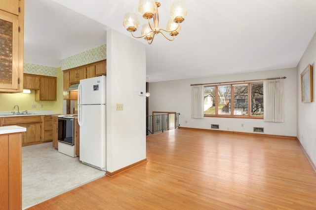 kitchen featuring white appliances, light countertops, a chandelier, brown cabinetry, and under cabinet range hood