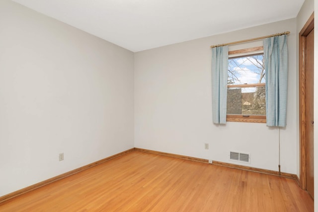 empty room featuring baseboards, light wood-style flooring, and visible vents
