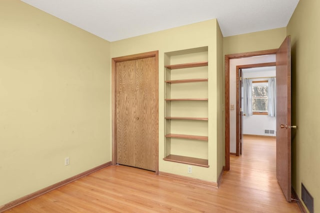 unfurnished bedroom featuring baseboards, visible vents, and light wood-style floors