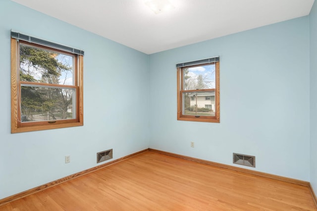 unfurnished room with visible vents, plenty of natural light, and wood finished floors