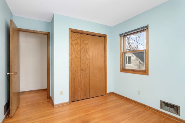 unfurnished bedroom with visible vents, baseboards, a closet, and light wood-type flooring