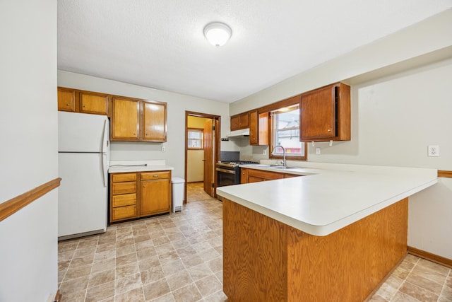 1622 Washington St NE, Minneapolis, MN 55413 - kitchen featuring a sink, freestanding refrigerator, brown cabinetry, light countertops, and stainless steel gas stove