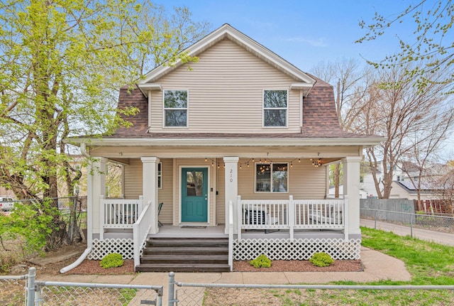 view of front of property with a porch, a shingled roof, and a fenced front yard