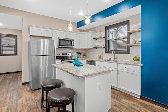 kitchen featuring white cabinets, open shelves, appliances with stainless steel finishes, a sink, and tasteful backsplash