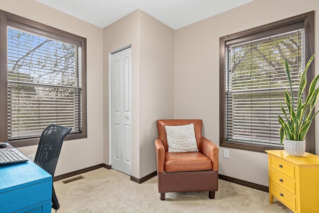 office space with baseboards, light colored carpet, a healthy amount of sunlight, and visible vents