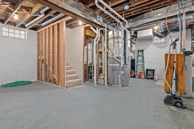 basement with heating unit, water heater, and stairway