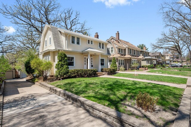 view of front facade featuring a residential view, a front lawn, an outbuilding, a chimney, and driveway