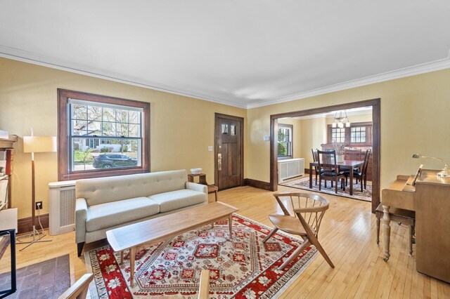 living room with crown molding, light wood finished floors, plenty of natural light, and a notable chandelier