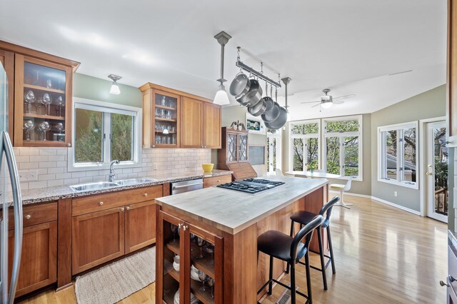 kitchen with brown cabinets, stainless steel appliances, decorative backsplash, and a sink
