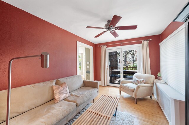 living room with a ceiling fan and light wood-style flooring
