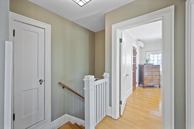 hallway featuring baseboards, light wood finished floors, and an upstairs landing