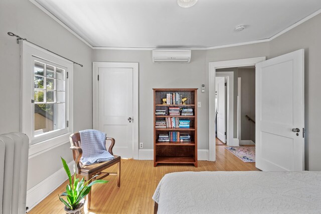 bedroom with an AC wall unit, radiator, baseboards, wood finished floors, and ornamental molding