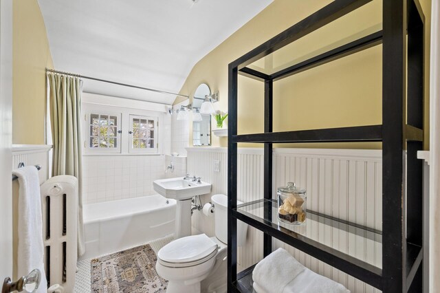 bathroom featuring tile walls, tile patterned flooring, shower / tub combo, a wainscoted wall, and toilet
